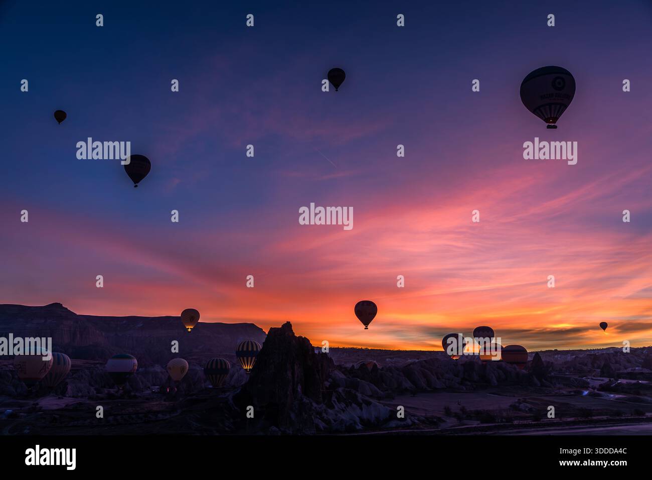 Hot air balloons rise above the rock formations of Göreme at sunrise, Central Anatolia Region, Turkey Stock Photo