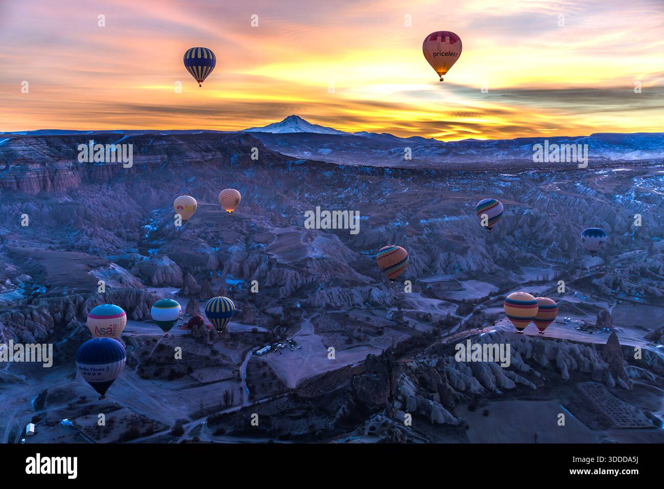 Hot air balloons float over Göreme, Central Anatolia Region, Turkey, with the Erciyes Dağı volcano in the background. Tuff stone landscape and fairy chimneys Stock Photo