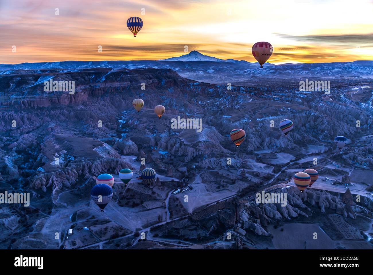 Hot air balloons float over Göreme, Central Anatolia Region, Turkey, with the Erciyes Dağı volcano in the background. Tuff stone landscape and fairy chimneys Stock Photo