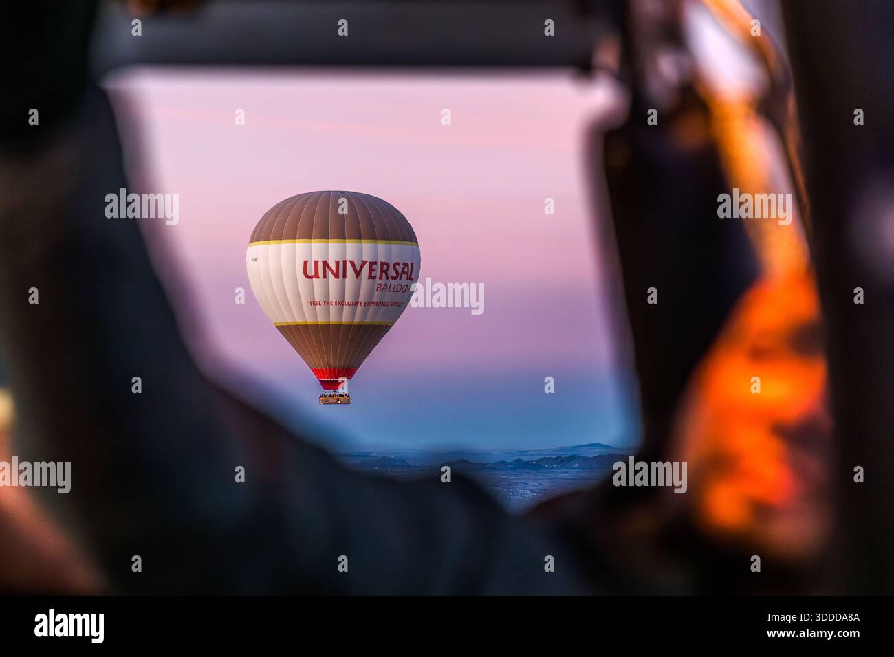 Hot air balloon from Universal Balloon flies over Göreme at sunrise, Central Anatolia Region, Turkey Stock Photo