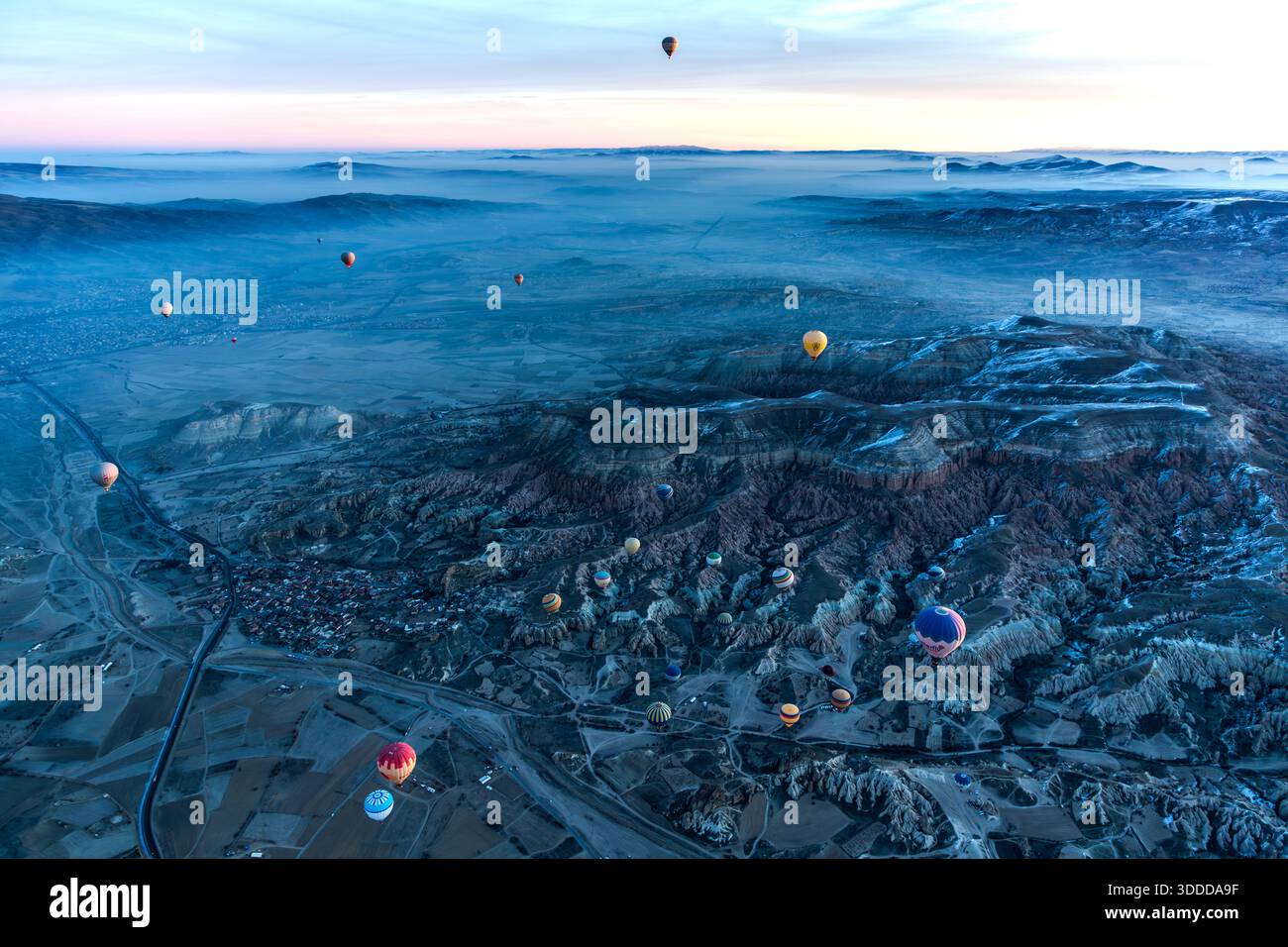 Hot air balloon flies over snow-covered landscape in Göreme, Central Anatolia Region, Turkey Stock Photo
