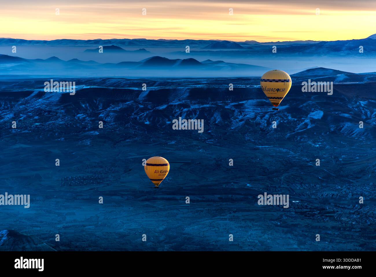 Hot air balloon flies over snow-covered landscape in Göreme, Central Anatolia Region, Turkey Stock Photo
