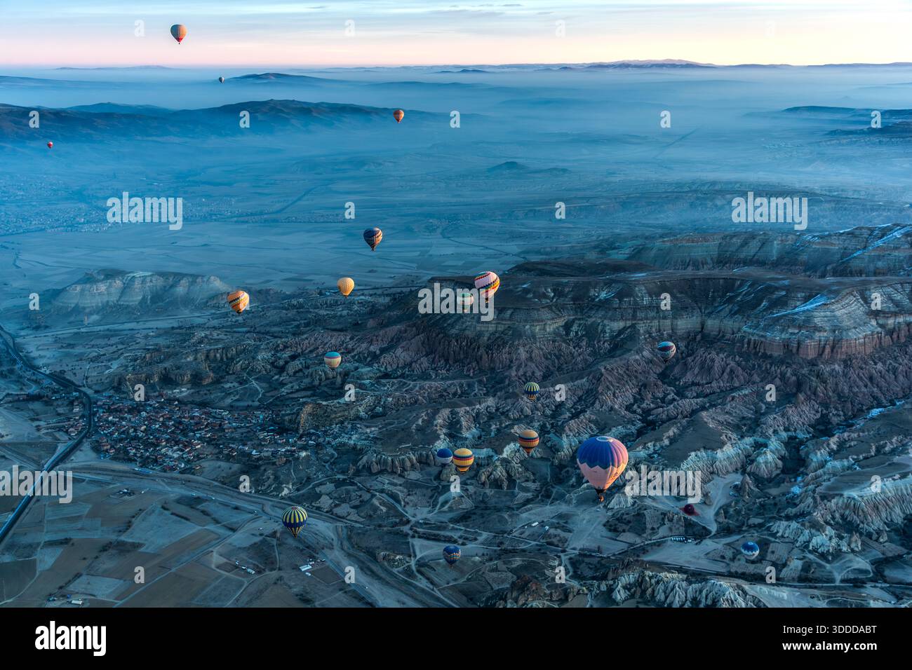 Hot air balloon flies over snow-covered landscape in Göreme, Central Anatolia Region, Turkey Stock Photo