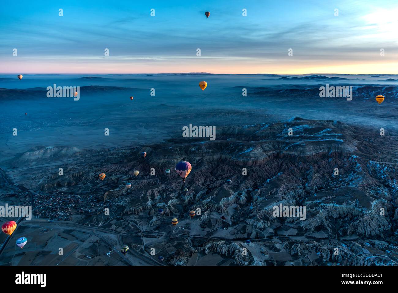 Hot air balloon flies over snow-covered landscape in Göreme, Central Anatolia Region, Turkey Stock Photo