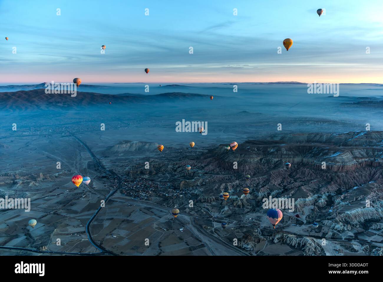 Hot air balloon flies over snow-covered landscape in Göreme, Central Anatolia Region, Turkey Stock Photo