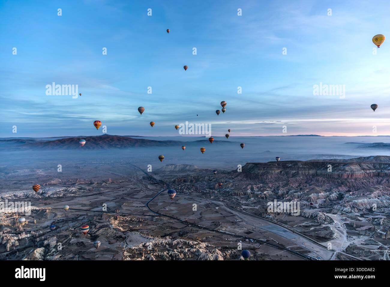 Hot air balloon flies over snow-covered landscape in Göreme, Central Anatolia Region, Turkey Stock Photo