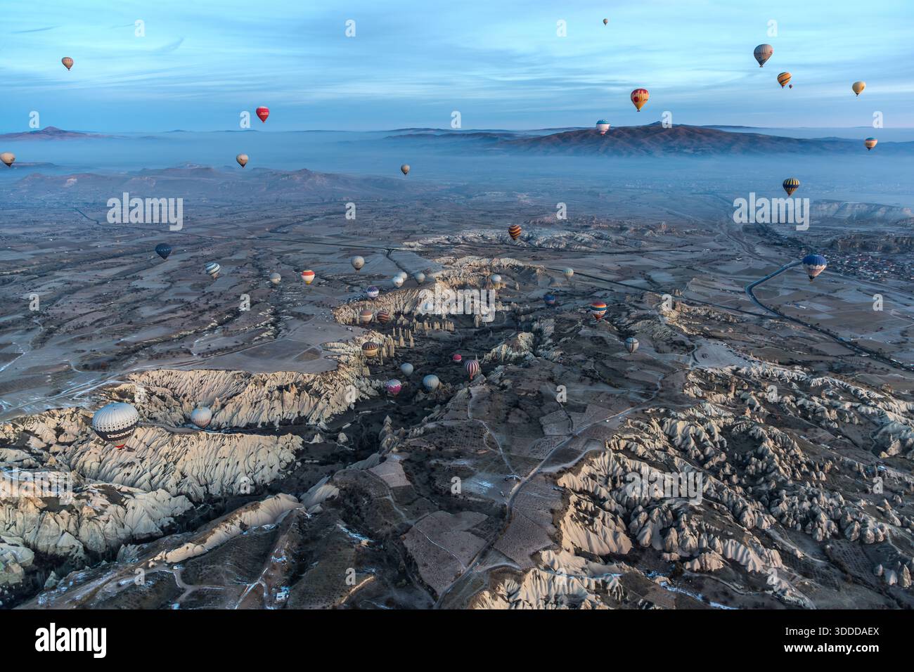 Hot air balloon flies over snow-covered landscape in Göreme, Central Anatolia Region, Turkey. Tuff stone landscape and fairy chimneys Stock Photo