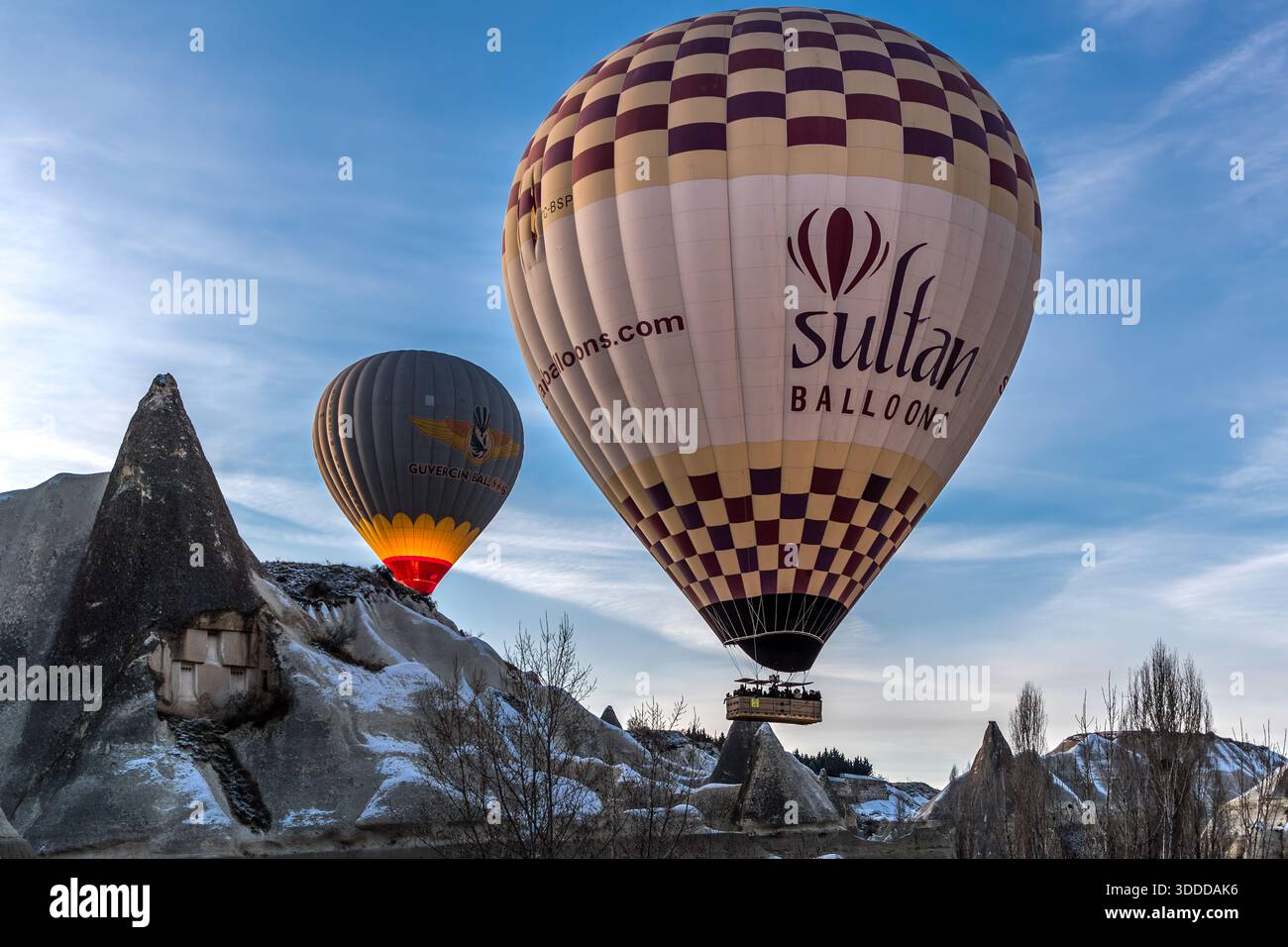 Hot air balloons from Sultan Balloons and Güvercin Balloons rise above rock formations in Göreme, Central Anatolia Region, Turkey. Tuff stone landscape and fairy chimneys Stock Photo