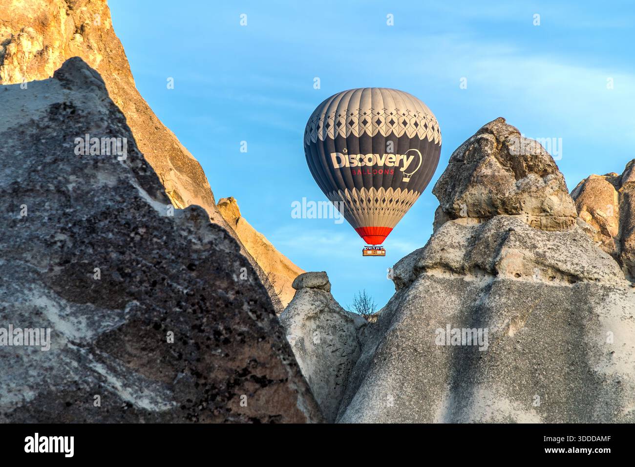 Discovery Balloons hot air balloon flies over rock formations in Göreme, Central Anatolia Region, Turkey. Tuff stone landscape and fairy chimneys Stock Photo