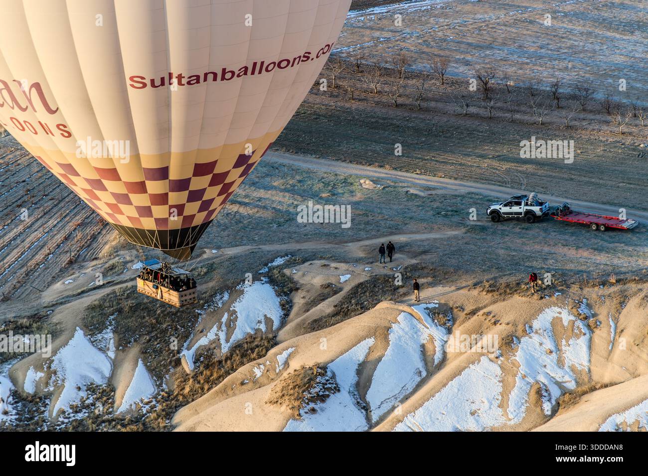 Sultanballoons hot air balloon flies over the snow-covered landscape of Göreme, Central Anatolia Region, Turkey Stock Photo