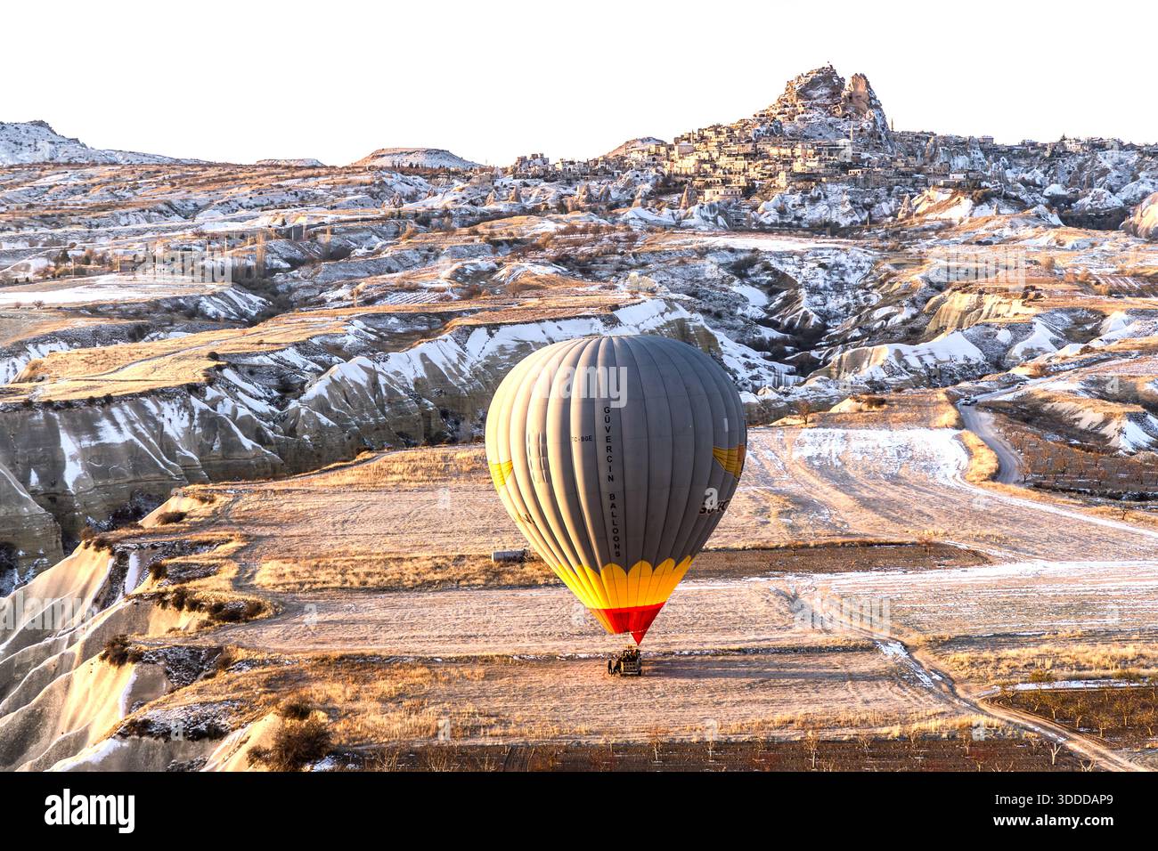 Sultanballoons hot air balloon flies over the snow-covered landscape of Göreme, Central Anatolia Region, Turkey Stock Photo