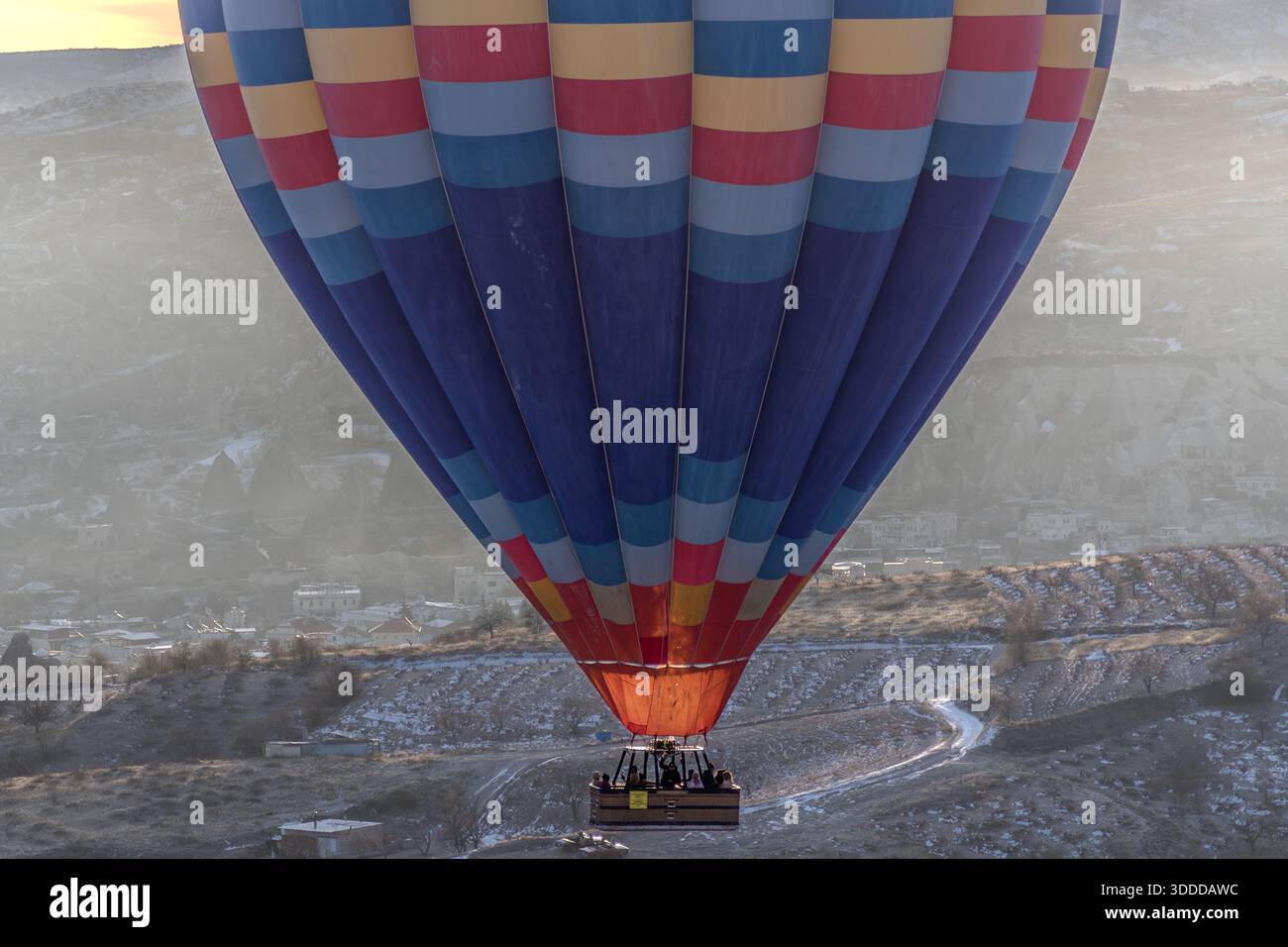 Colourful hot air balloon with passengers floats above Göreme, Central Anatolia Region, Turkey Stock Photo
