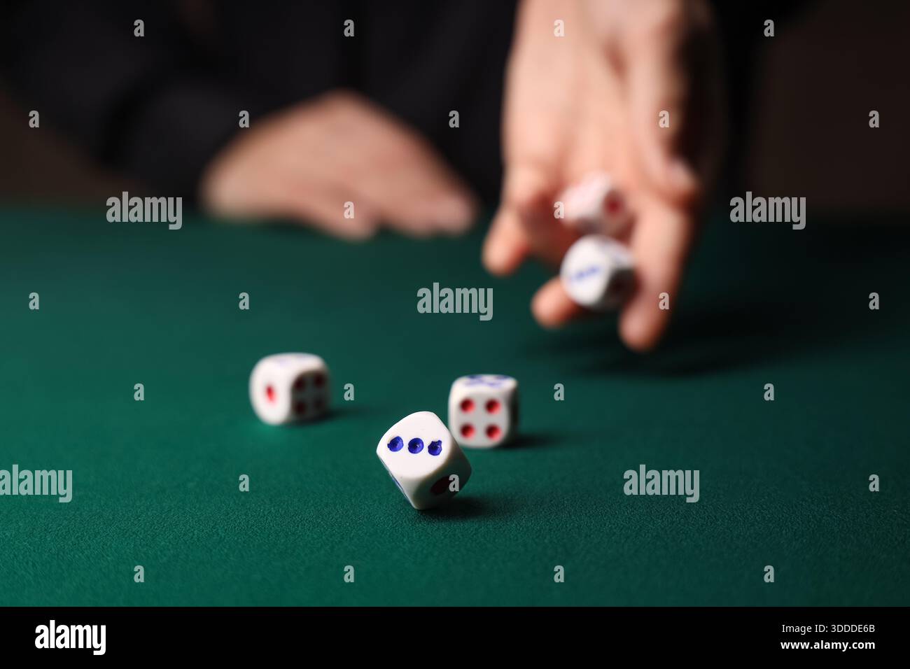 Man throwing white game dices on green table, closeup Stock Photo