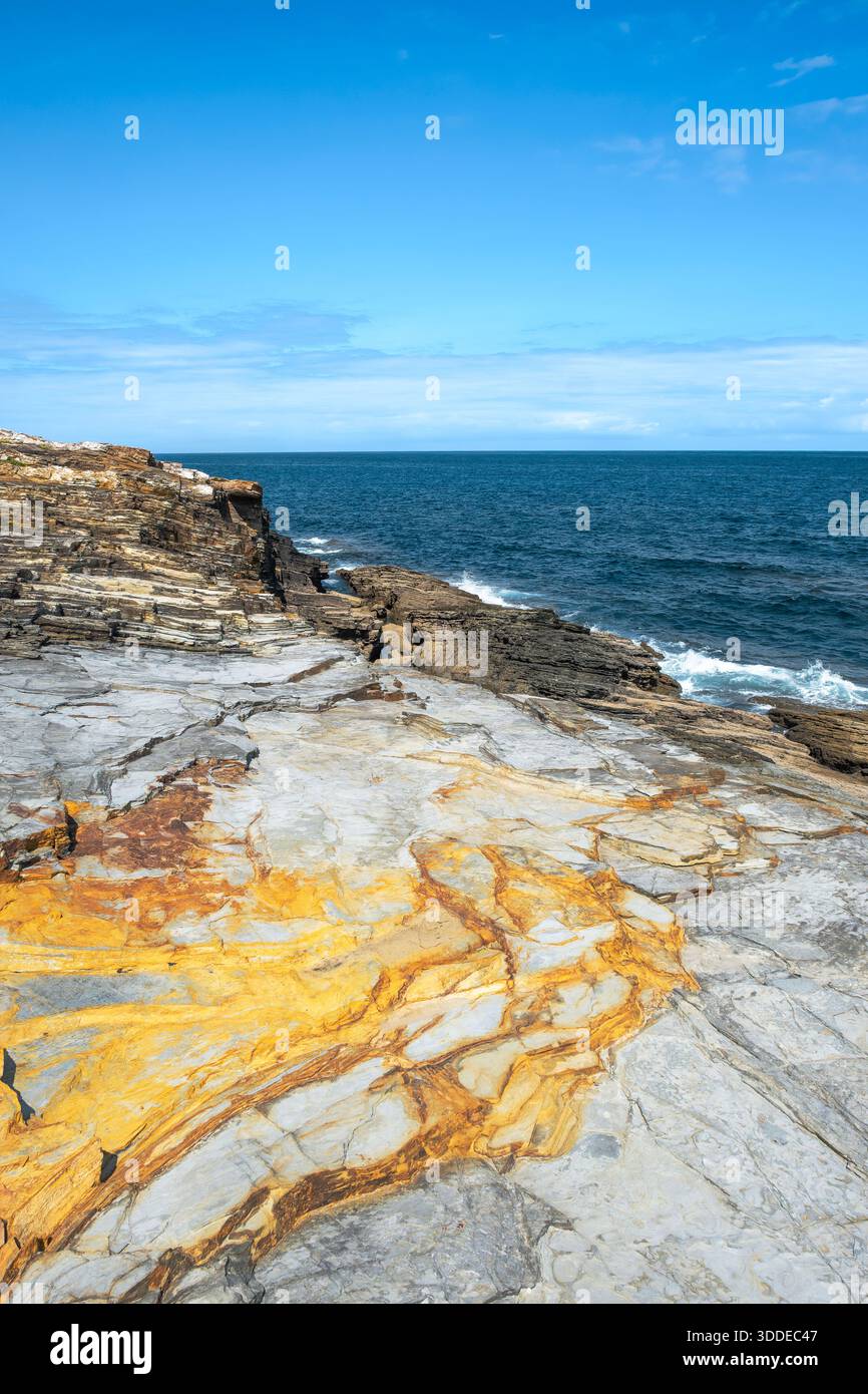 Striking geological formation with golden mineral stain on gray layered ...
