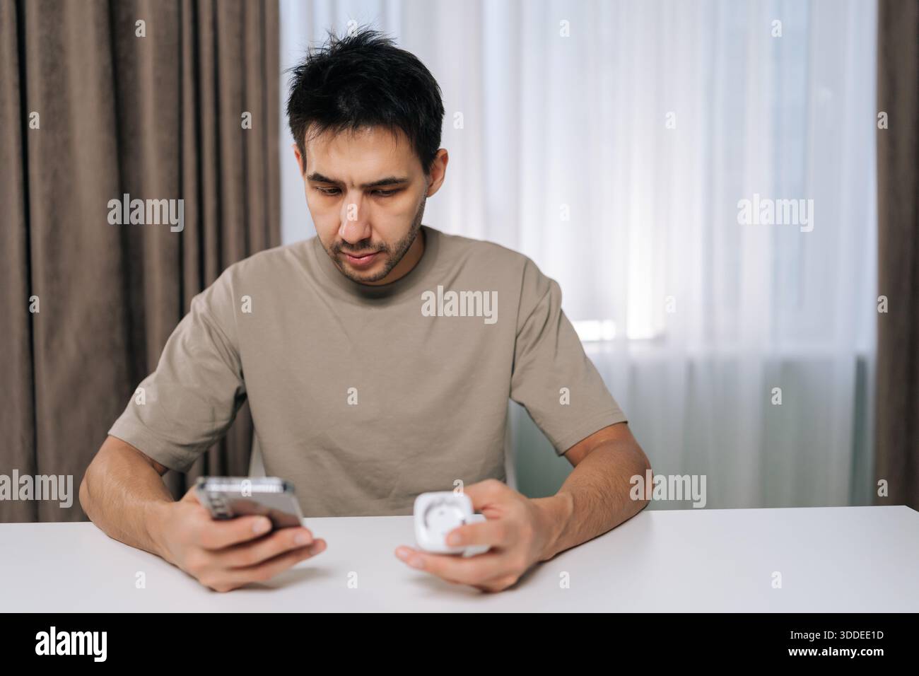 Man connecting smart home device using smartphone, looking at application settings, setting up and controlling smart socket from mobile app, exploring Stock Photo