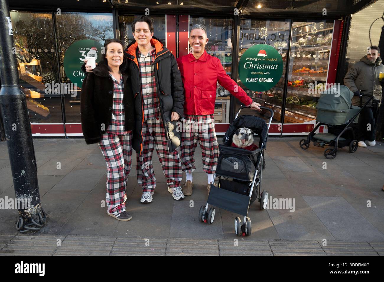 London Hackney London Fields,  Christmas Day in Broadway market. Friends  in matching pyjamas  with a bull dog in a pram. Stock Photo