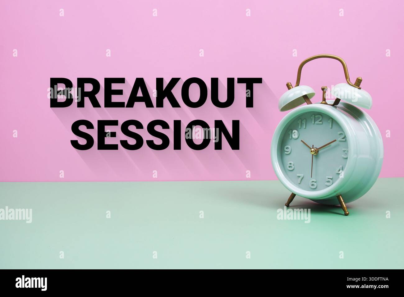 Black alarm clock on a pastel green and pink background with the text "Breakout session" Stock Photo
