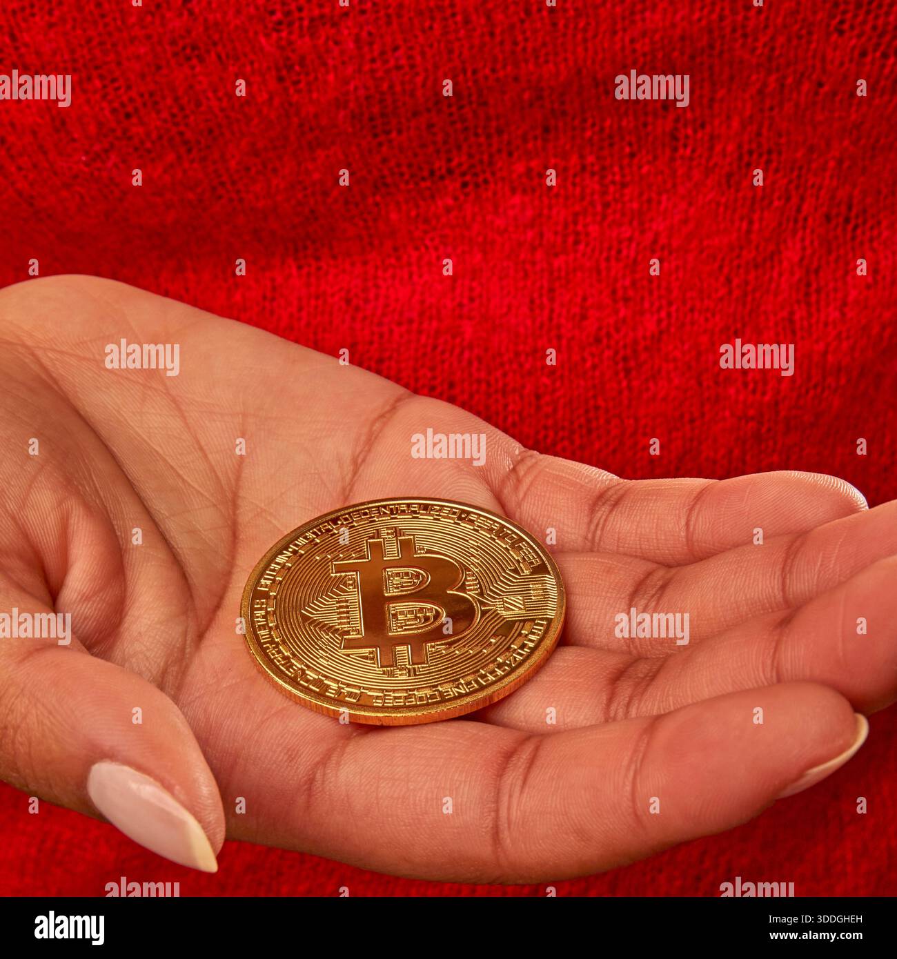 A person is holding a round coin with the Bitcoin logo in their hands. The  setting is casual, and the person appears focused on the coin Stock Photo -  Alamy
