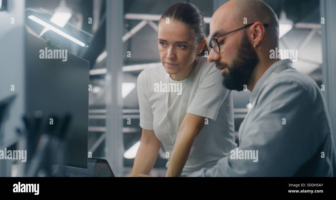 Engineers Reviewing Network Performance Data. Male and Female IT Engineer Team Collaborating Over Computer Monitor to Review Critical Network Performance Metrics. Teamwork and Real Time IT Monitoring. Stock Photo