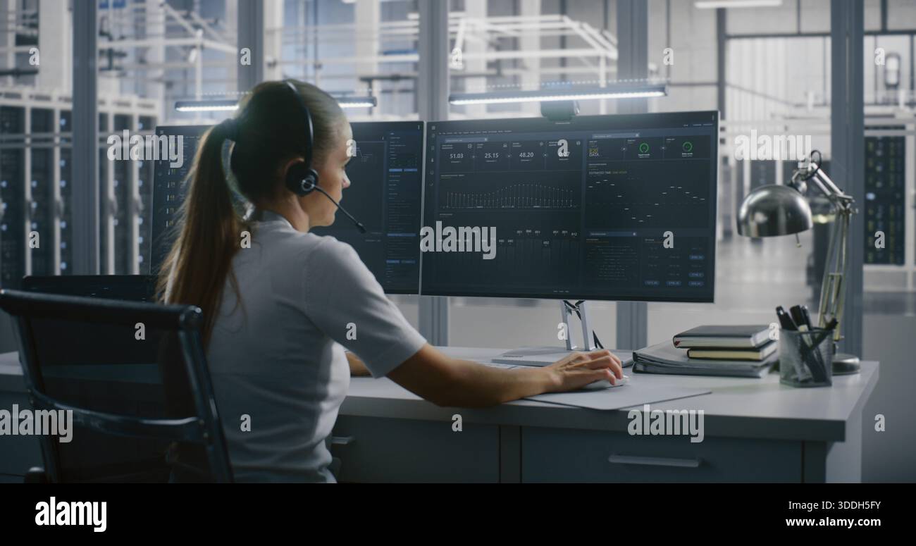 Female Technical Specialist Communicates Via Headset While Tracking Metrics and Graphs Data on Multi Screen Setup in Data Center. Control and Support, Expert Consultation, and Complex Problem Solving. Stock Photo