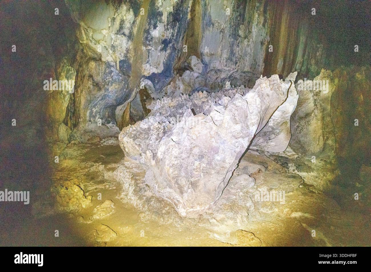 A jagged limestone boulder dominates the shadowy interior of Phu Kham ...