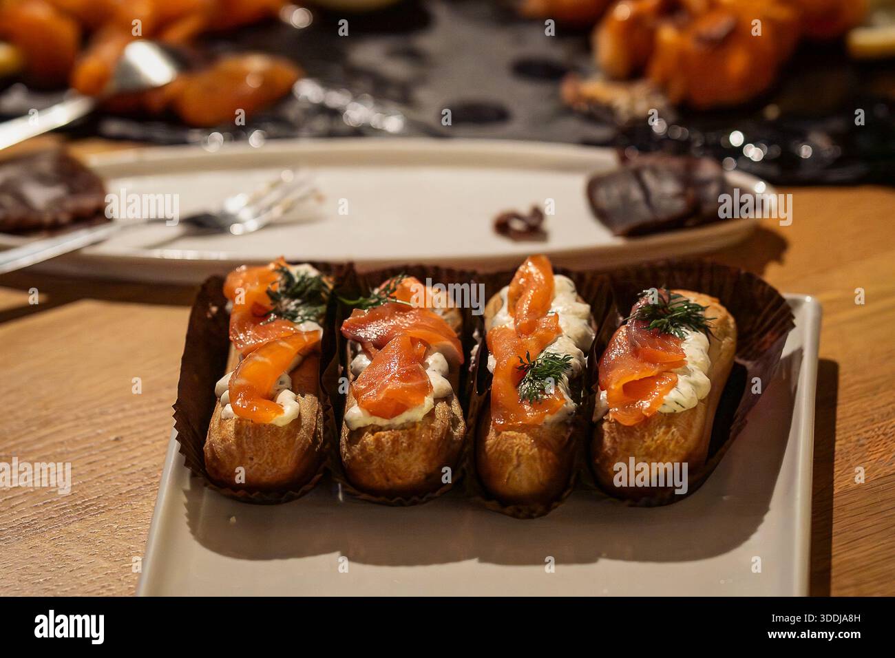 Close-up of smoked salmon éclairs. Gourmet savory éclairs filled with cream cheese and topped with smoked salmon, served as elegant appetizers. Stock Photo