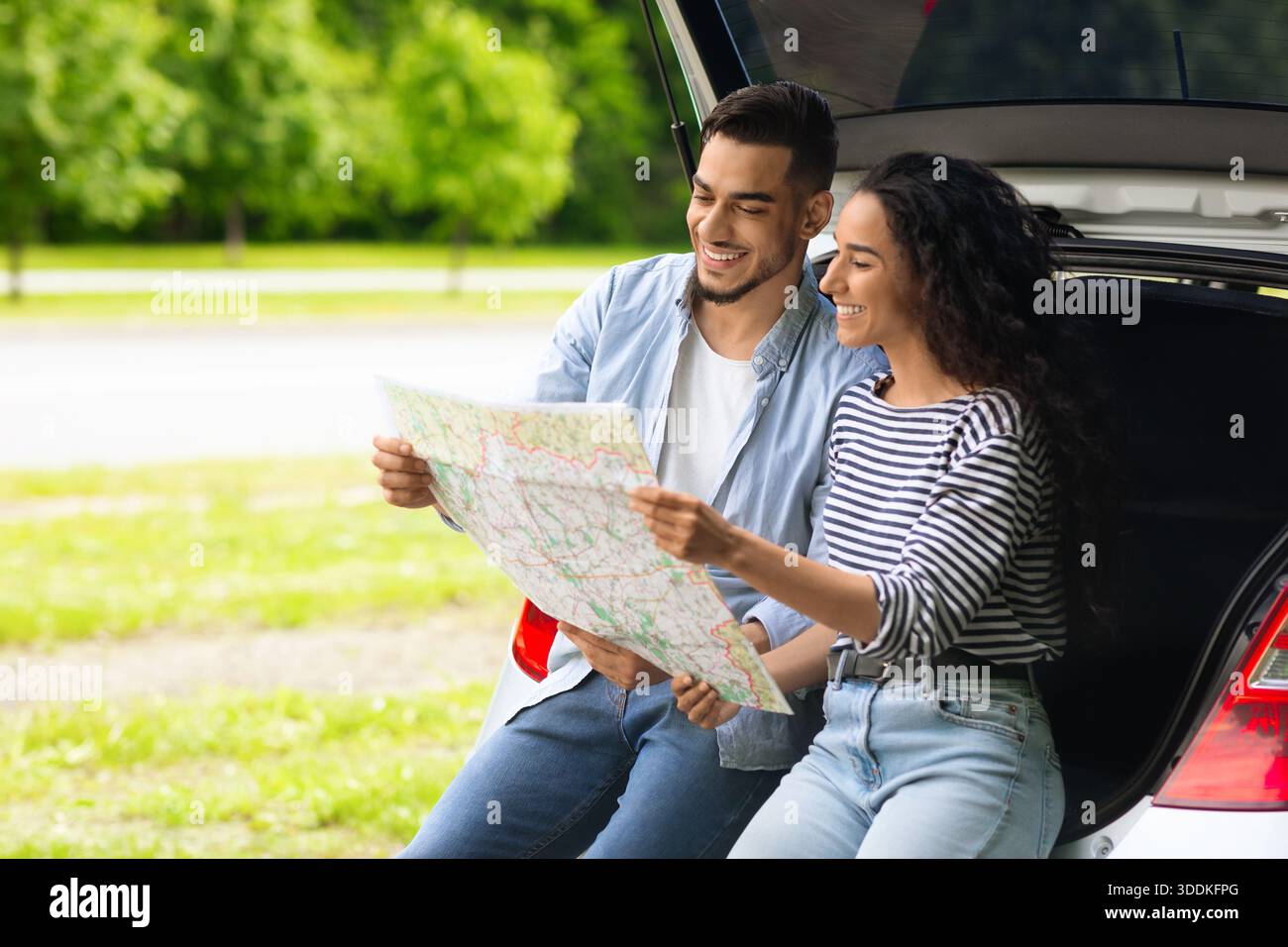 Loving middle-eastern couple watching map while having break, copy space Stock Photo