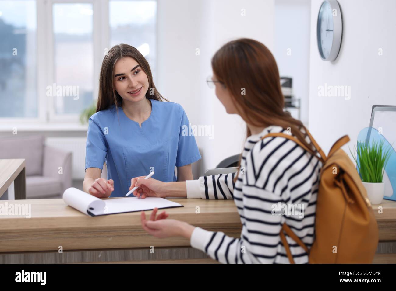 Medical assistant helping patient at reception in clinic Stock Photo ...