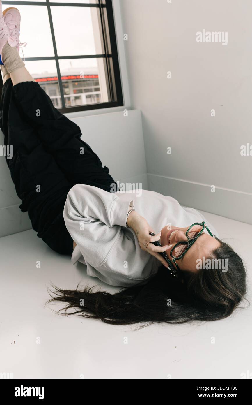Woman relaxing on floor talking on smartphone Stock Photo