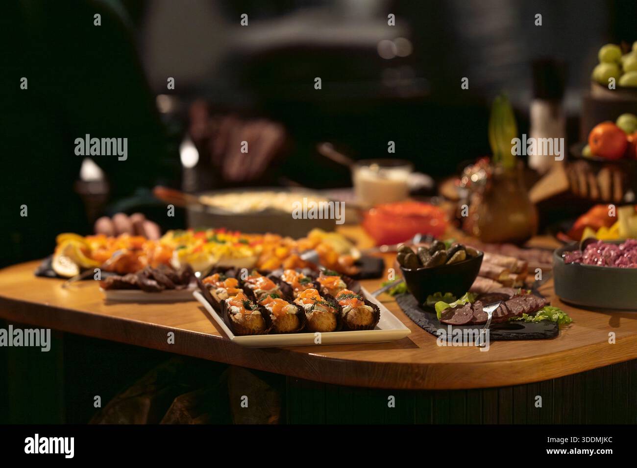 Elegant catering buffet with smoked salmon, cold cuts and devilled eggs arranged on a wooden table. Luxury event buffet featuring gourmet appetizers. Stock Photo