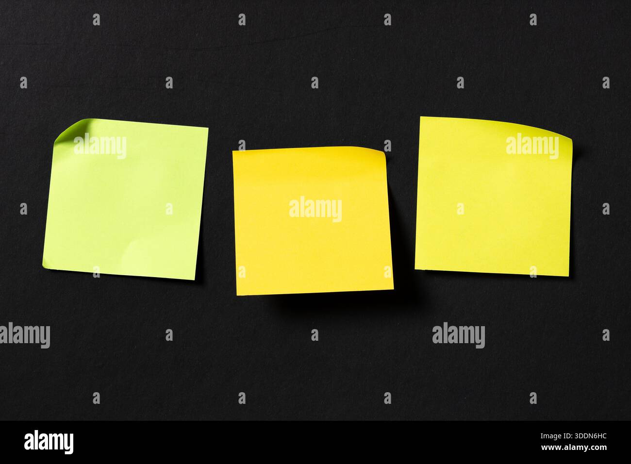 Three blank colorful sticky notes on black wall. Template mock up Stock Photo