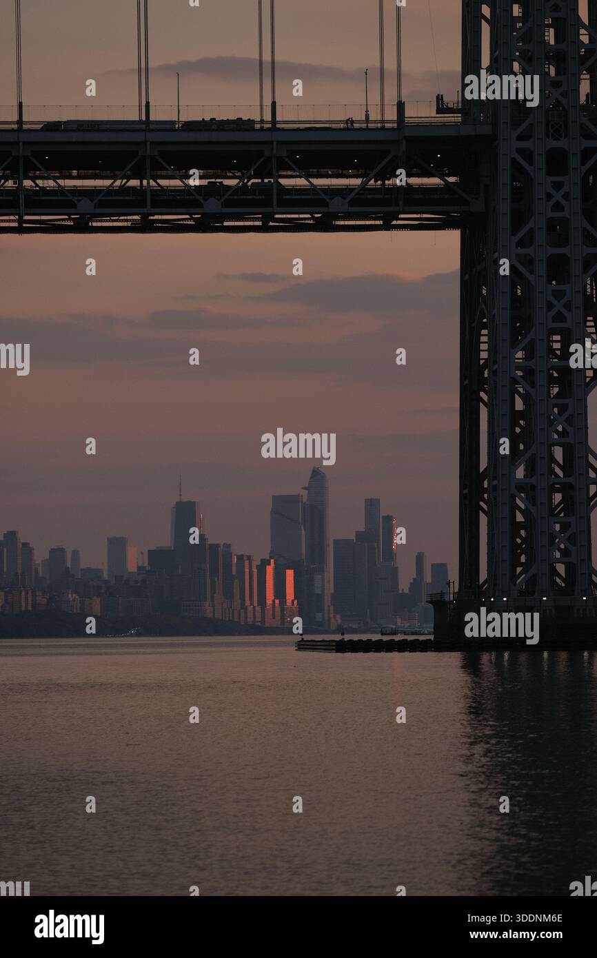 New York city skyline at sunset with bridge silhouetted against the evening sky Stock Photo