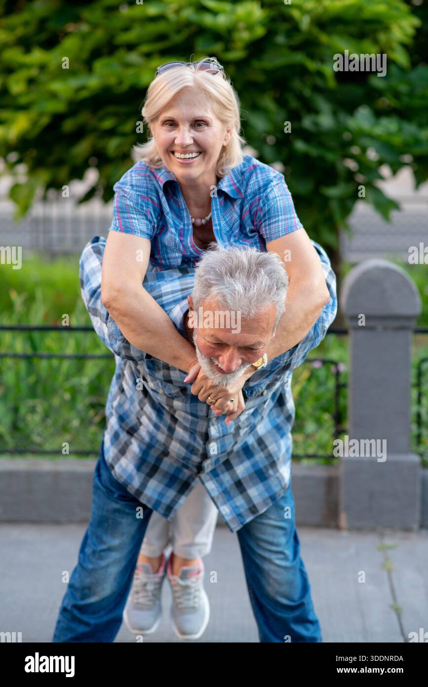 Happy senior couple having fun and enjoying outdoor piggyback ride Stock Photo