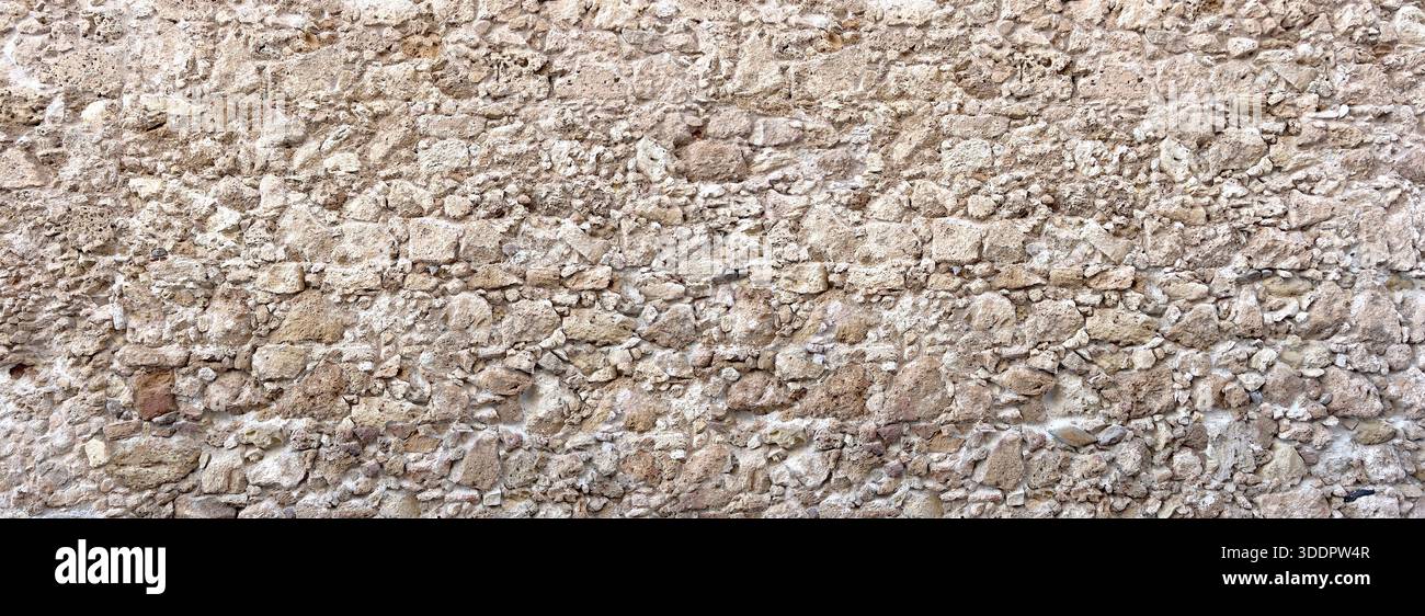 Rustic stone wall featuring ancient masonry with a textured surface, ideal for backgrounds Stock Photo