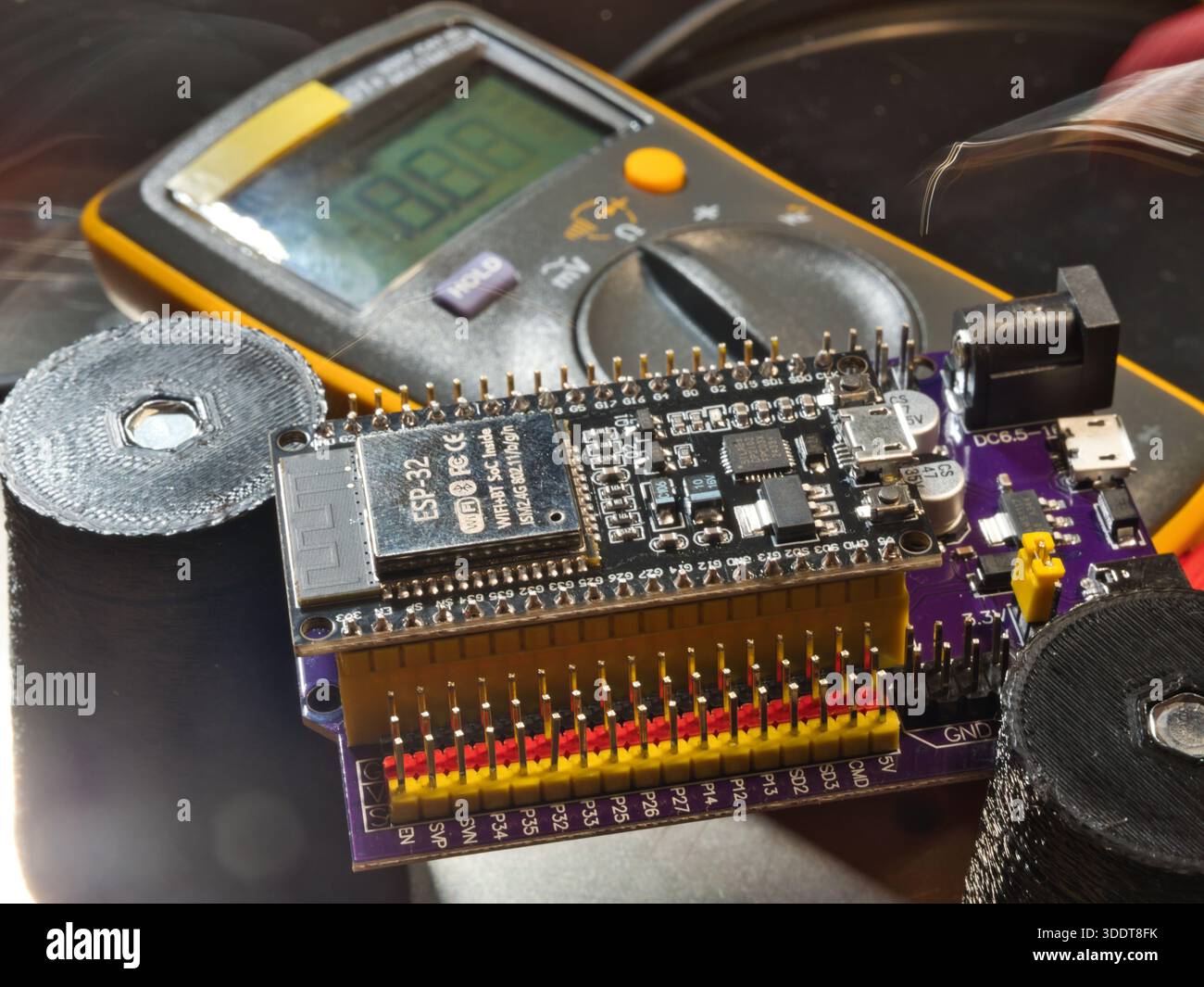 Engineer testing microcontroller board.; Close-up of an engineer testing voltage on a modern microcontroller development board (PCB) using a digital m Stock Photo