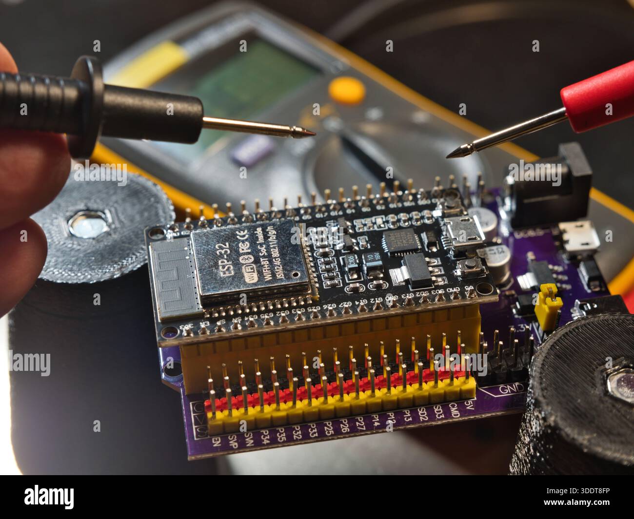 Engineer testing microcontroller board.; Close-up of an engineer testing voltage on a modern microcontroller development board (PCB) using a digital m Stock Photo