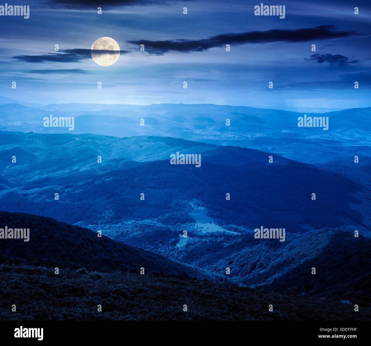 mountain landscape with rolling hills at night. summer countryside scenery with view in to the distant valley and forested slopes in full moon light. Stock Photo