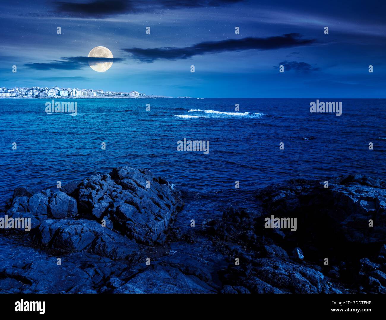 rocky shore of the sea coast under blue sky at night. beautiful view of coastal scene in full moon light. resort scenery during vacation season in sum Stock Photo
