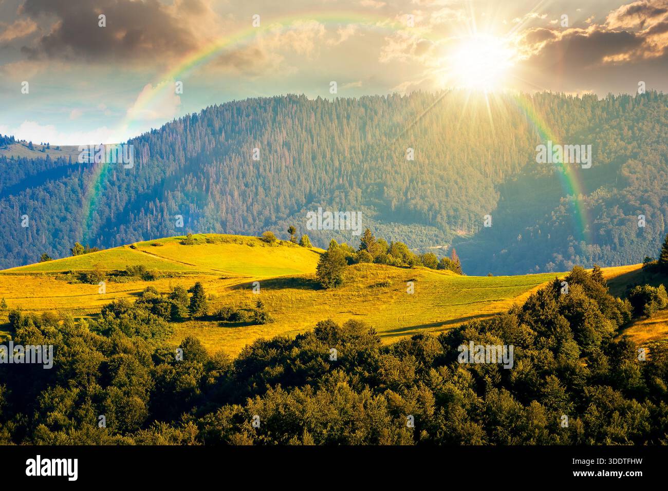 mountainous countryside landscape with rolling hills on summer sunset. rural area in evening light. beautiful view of place with green grassy pastures Stock Photo