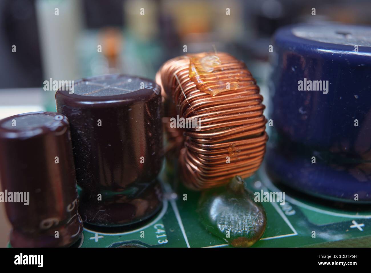 Copper inductor on an inductrial electronic board. Electromagnetic component with capacitors. Stock Photo