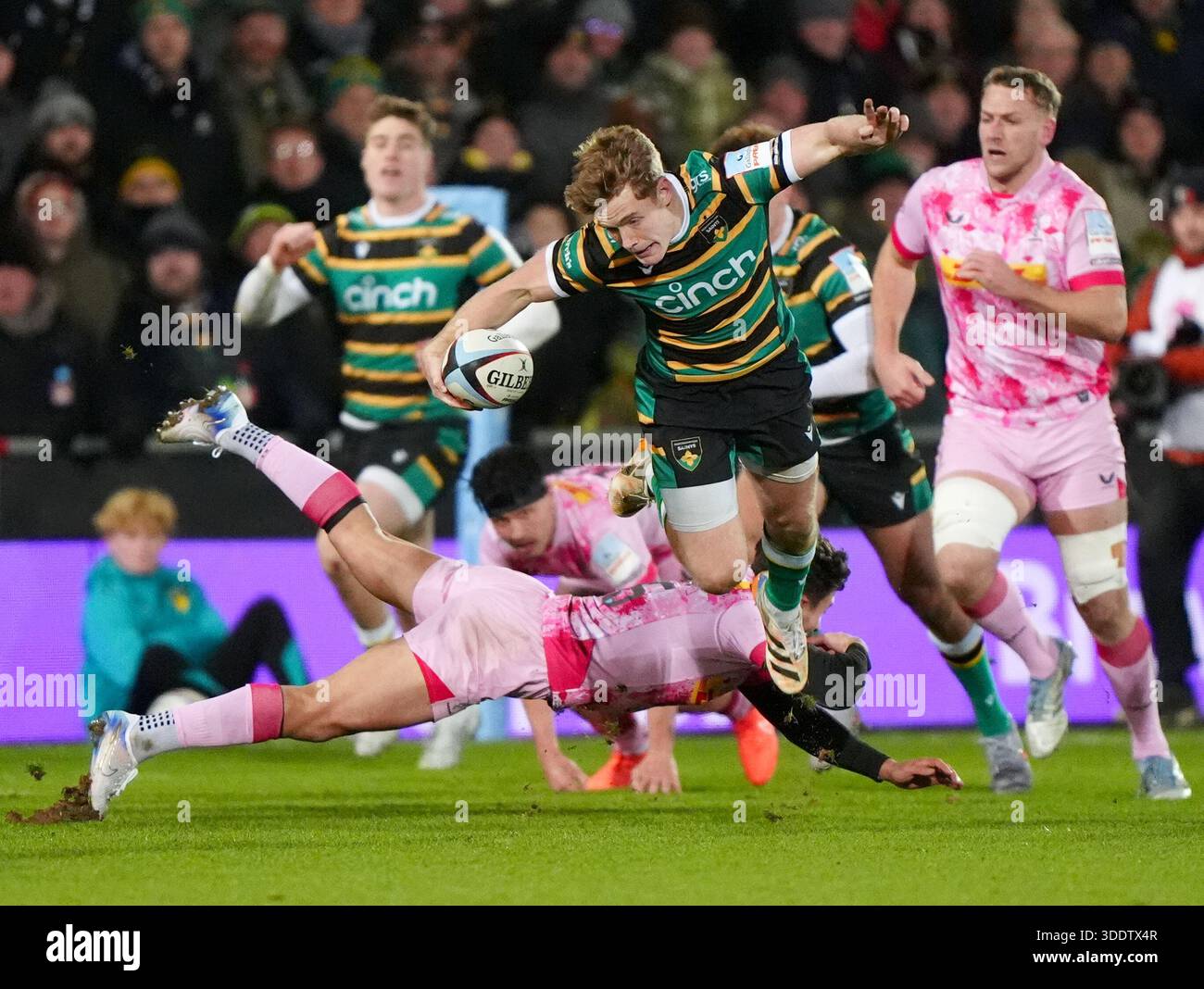 Northampton Saints' Fin Smith jumps over Harlequins' Sam Riley during ...