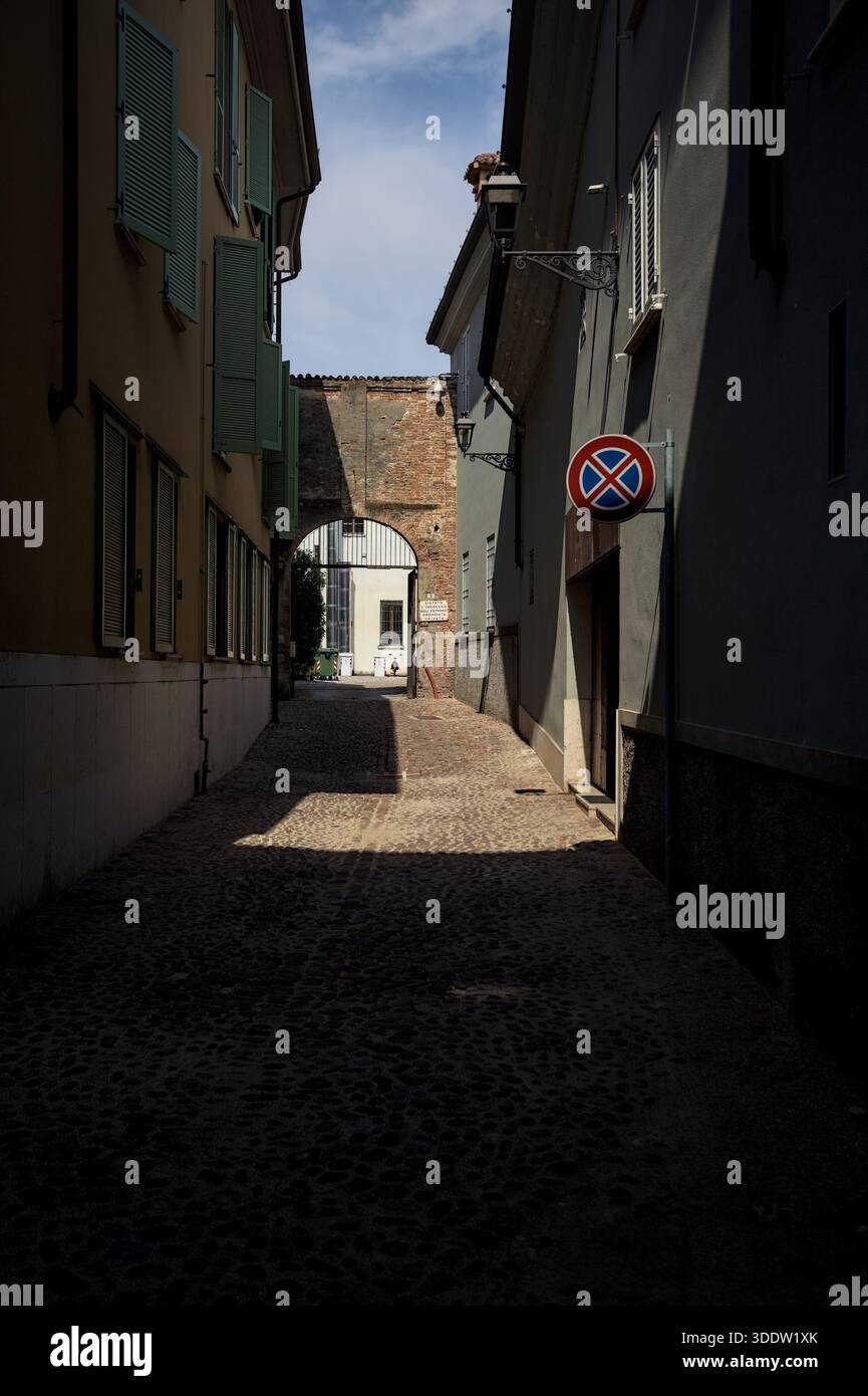 Dead end alley half in the shade with an open gate at its end on a sunny day in an italian town Stock Photo