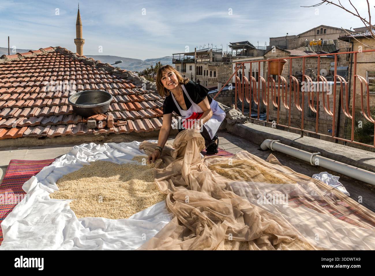 Sevil Halıcı Ayhan dries mantı noodles on the roof above the Tık Tık Kadın Emeği restaurant. Ürgüp, Central Anatolia Region, Turkey Stock Photo
