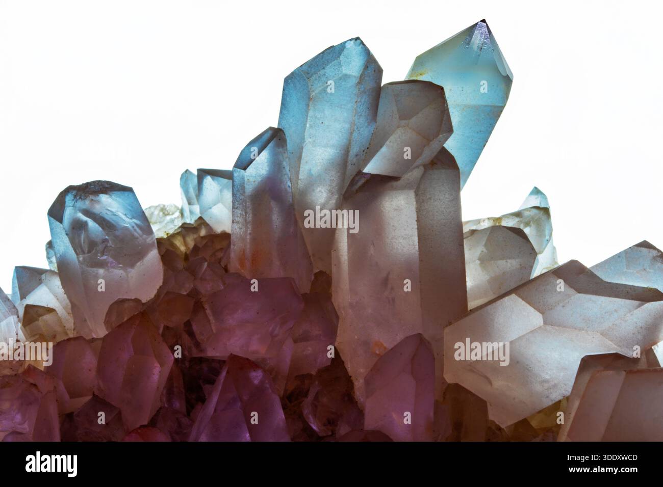 High contrast macro shot of natural quartz crystals featuring sharp geometric terminations and soft purple to blue ethereal light refractions Stock Photo