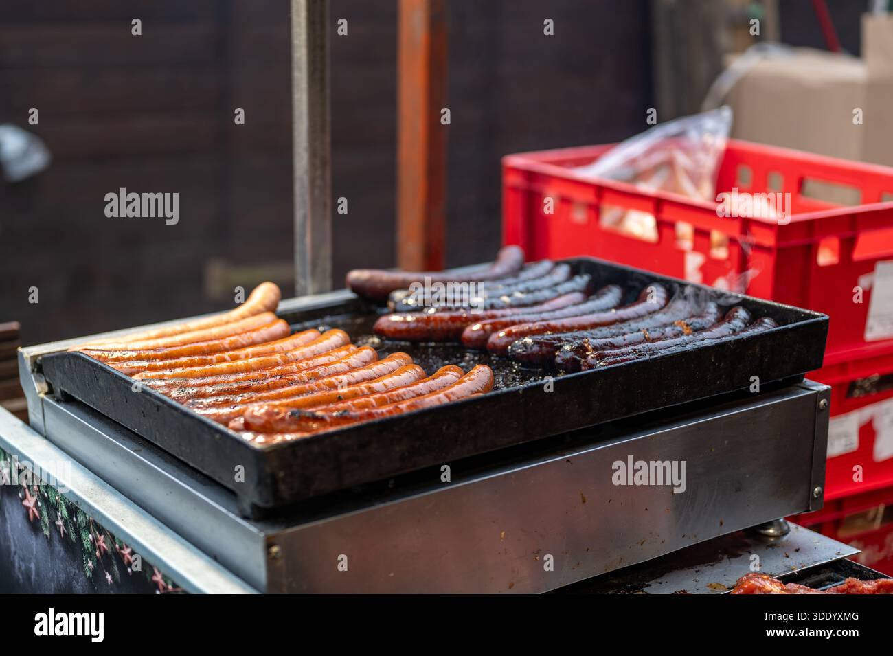 Close up view of grill at christmas market stall with sausages and meat cooking over hot coals, street food scene with smoke, heat and traditional win Stock Photo