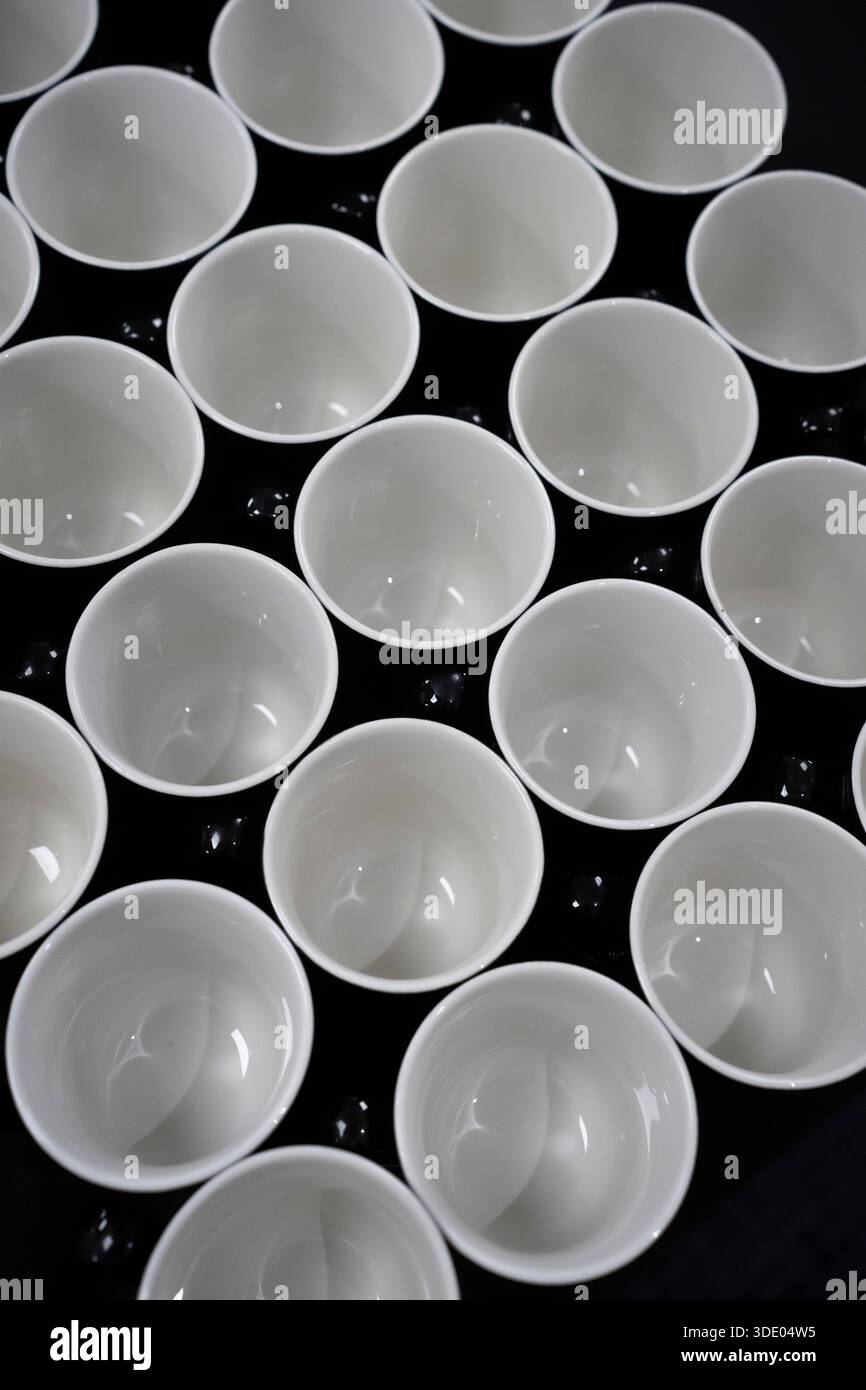 White cups are arranged on a black surface Stock Photo