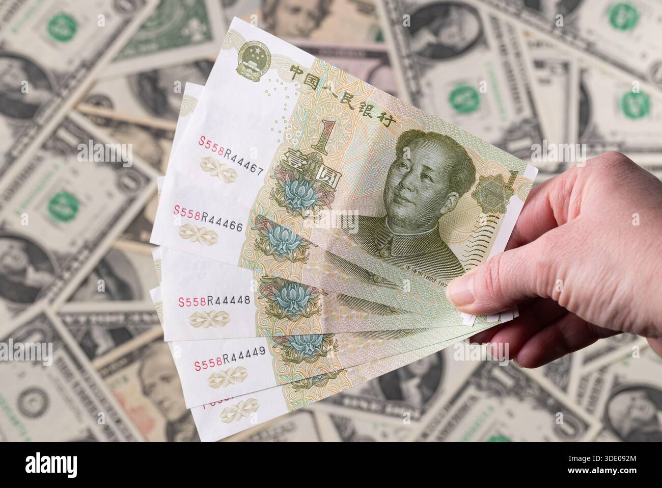 Hand Holding Chinese Yuan Over US Dollar Background Stock Photo - Alamy