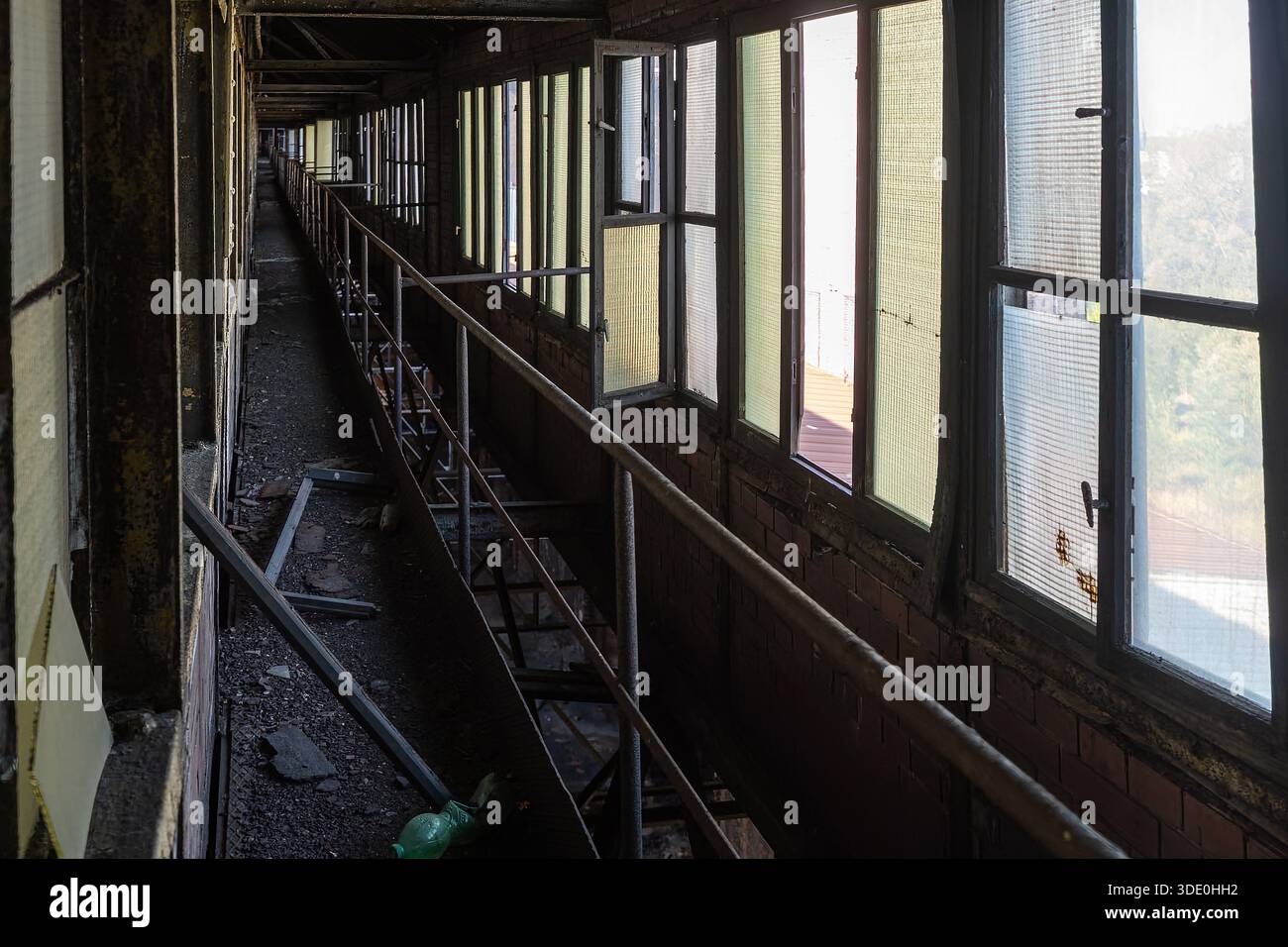 Long abandoned industrial corridor with metal railing and rows of ...