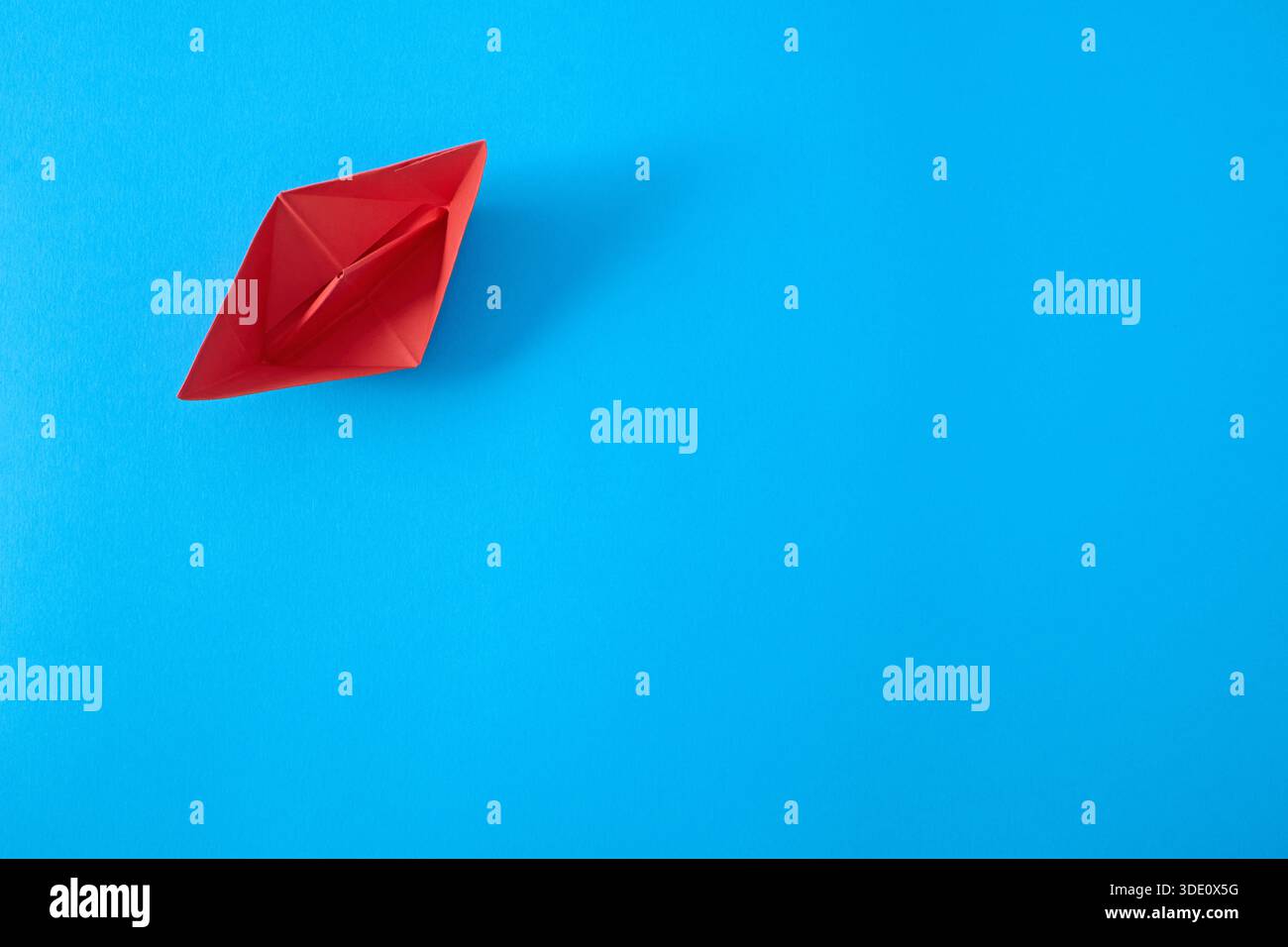 Red paper ship on blue background, top view Stock Photo