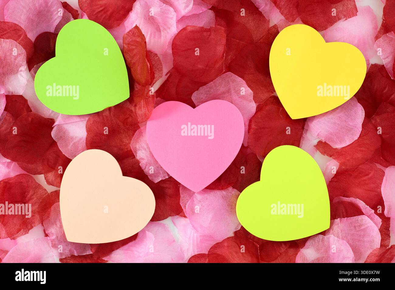 Heart shape sticky notes laying on rose petals Stock Photo